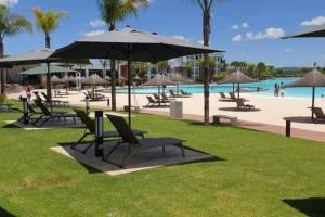 a group of chairs and umbrellas next to a pool at Crystal lagoon View 3Bed Apartment in Pretoria
