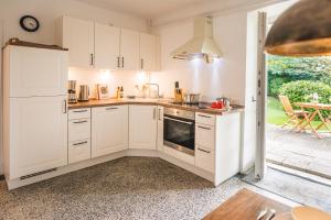 a kitchen with white cabinets and a stove top oven at FEWO Seeblick in Glücksburg