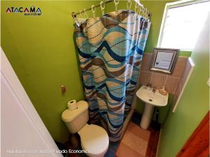 y baño con aseo y cortina de ducha. en Hostal Atacama Ancestral, en San Pedro de Atacama