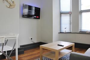 a living room with a table and a tv on the wall at Small Home Big Welcome in Margate