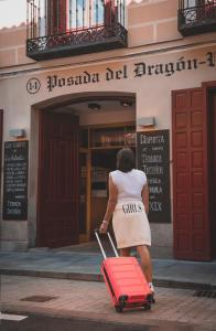 Uma mulher a puxar uma mala vermelha em frente a um edifício. em Posada del Dragón Boutique Hotel em Madri