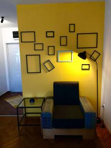 ein Zimmer mit einem Stuhl und einer gelben Wand mit Bildern in der Unterkunft Apartman 2411 in Valjevo