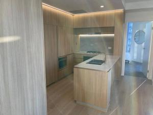 una cocina con armarios de madera y fregadero en Lovely 2 Bedroom Executive Apartment en Brisbane