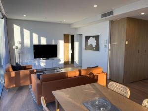 ein Wohnzimmer mit einem Sofa und einem TV in der Unterkunft Lovely 2 Bedroom Executive Apartment in Brisbane