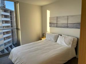 1 dormitorio con cama blanca y ventana grande en Lovely 2 Bedroom Executive Apartment, en Brisbane