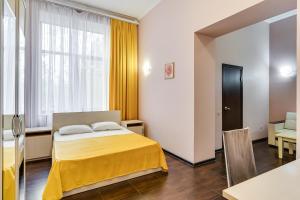 a bedroom with a bed and a yellow blanket at Ostrovsky Hotel in Rostov on Don
