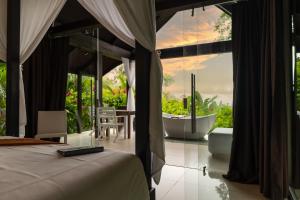 a bedroom with a tub and a bed with a view at Oxygen Jungle Villas & Spa in Uvita