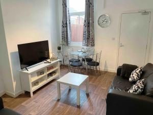 a living room with a couch and a tv and a table at Homely 3 Bed Town house in Coventry City Centre in Coventry
