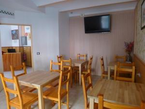 a dining room with wooden tables and chairs and a flat screen tv at Pension El Ciervo in Lloret de Mar