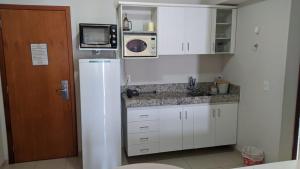 a white kitchen with a refrigerator and a microwave at Águas da Serra Apart Hotel in Rio Quente