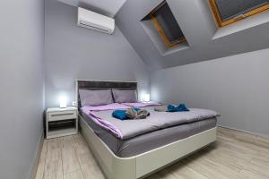 ein Schlafzimmer mit einem Bett mit violetter Bettwäsche und zwei Leuchten in der Unterkunft Beautiful 1BD Apartment with a Parking Spot in Plowdiw