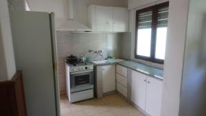 a white kitchen with a stove and a window at Casa Los Jardines in Chascomús