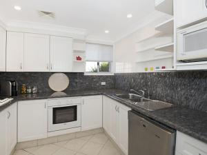 a white kitchen with white cabinets and a sink at Werrina Townhouse in The Entrance