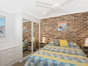 Un dormitorio con una cama y una pared de ladrillo. en Werrina Townhouse, en The Entrance