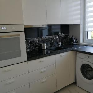 uma cozinha branca com um lavatório e uma máquina de lavar louça em Apartament Classic Południe em Włocławek