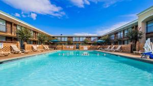 einen Pool in einem Hotel mit Stühlen und einem Gebäude in der Unterkunft Best Western Greenville Airport in Greenville