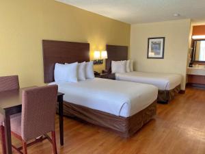 a hotel room with two beds and a table and chairs at Best Western Greenville Airport in Greenville +9 photos