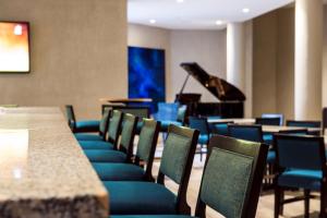 a room with a table and chairs and a piano at Radisson Blu Mammy Yoko Hotel in Freetown