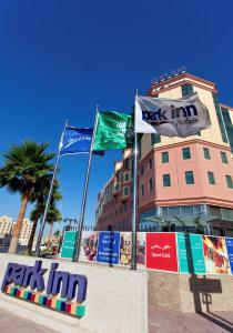 アル・コバールにあるパーク イン バイ ラディソン アル コバールの前に3つの旗が立っている建物