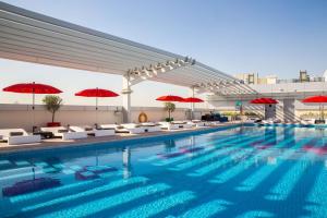una piscina con sombrillas rojas en un edificio en Park Inn by Radisson Dubai Motor City en Dubái