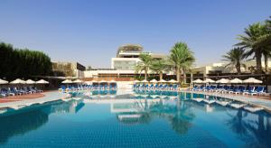 a large swimming pool with chairs and umbrellas at Radisson Blu Hotel, Kuwait in Kuwait