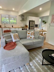 a living room with a gray couch and a kitchen at Maleny Lake Cottages in Maleny