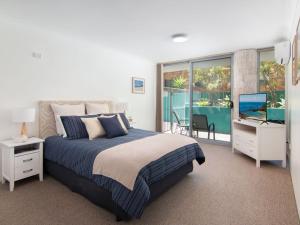 een slaapkamer met een bed, een televisie en een balkon bij Shores G1 on Head Street close to Main Beach in Forster