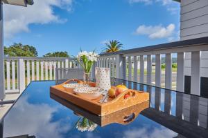 a table with a bowl of fruit on a balcony at Longitude Apartments Raglan in Raglan