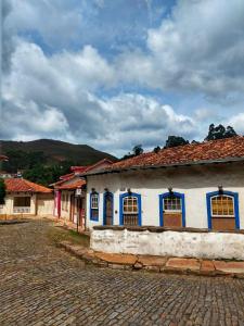 a white building with blue windows on a cobblestone street at Aconchego do Pilar in Ouro Preto