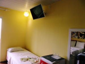 a room with two beds and a tv on the wall at Pousada TonaPraia in Florianópolis