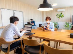 ゲストハウス五島時光 في غوتو: يجلس شخصان على طاولة مع الكمبيوتر المحمول