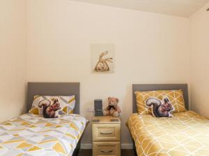 two beds with teddy bears sitting on them in a bedroom at The Wee Lodge in Glendevon