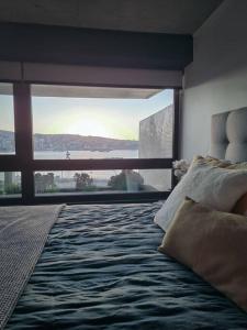 Schlafzimmer mit einem Bett und einem großen Fenster in der Unterkunft Nuevo Departamento Vive Barón Valparaíso in Valparaíso