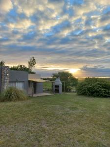 a house in a field with the sunset in the background at Acceso Viejo Casas de Campo in La Cumbre