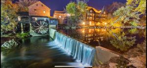 a river with a wooden house and a watermill at Luxury condo in the heart of Pigeon Forge in Pigeon Forge