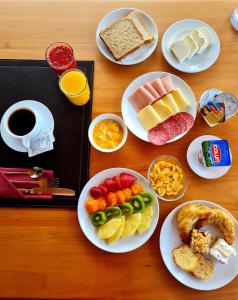 - une table avec des assiettes de nourriture et un plateau de produits pour le petit-déjeuner dans l'établissement Hotel Gran Pacifico, à Puerto Montt