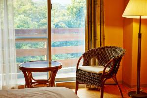 Zimmer mit einem Stuhl, einem Tisch und einem Fenster in der Unterkunft Iriomotejima-Jungle Hotel Painumaya in Iriomote