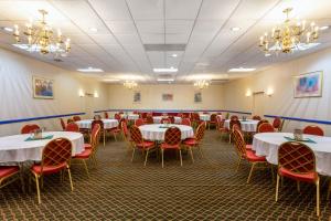 a dining room with white tables and red chairs at Baymont by Wyndham Queensbury/Lake George in Queensbury