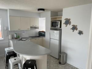 a kitchen with a refrigerator, stove, sink and microwave at Nautilus Resort Mooloolaba in Mooloolaba