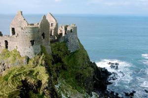 a castle on a cliff next to the ocean at Craigalappan Cottages Holiday Home in Bushmills