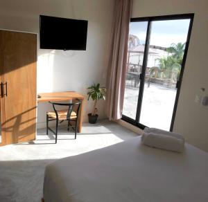 sypialnia z łóżkiem, biurkiem i telewizorem w obiekcie Black flamingo w mieście Isla Holbox