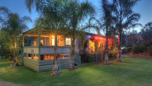 a house with lights on in a yard with trees at River Bend Caravan Park in Kanyapella