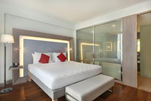 a bedroom with a large white bed with red pillows at Noble Resort Hotel Melaka in Malacca