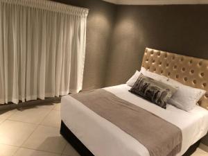 een slaapkamer met een groot bed met witte lakens en kussens bij Charli’s Lodge in Mpheleng