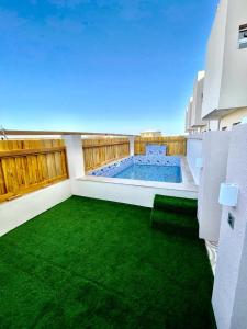 a balcony with a swimming pool and green grass at Al Asala Resort in Al Ruwis