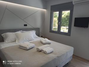 a bedroom with two towels on a bed with a window at VARKIZA VIEW APARTMENT in Varkiza