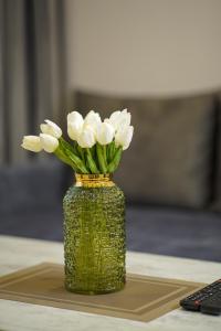 un jarrón con flores blancas en una mesa en Koghbatsi Aparthotel en Ereván