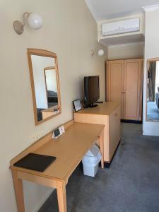 a room with a desk with a television and a mirror at The Oxley Motel Dubbo in Dubbo