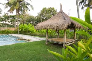 a hut with a bench next to a swimming pool at Roemah Nelayan in Montongbuwoh