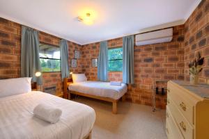 a bedroom with two beds in a brick wall at Swan Cove in Coles Bay +7 photos